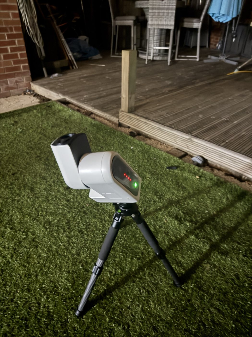 The Seestar S30 Pro on its tripod and EQ wedge on the lawn at night, arm raised mid-alignment