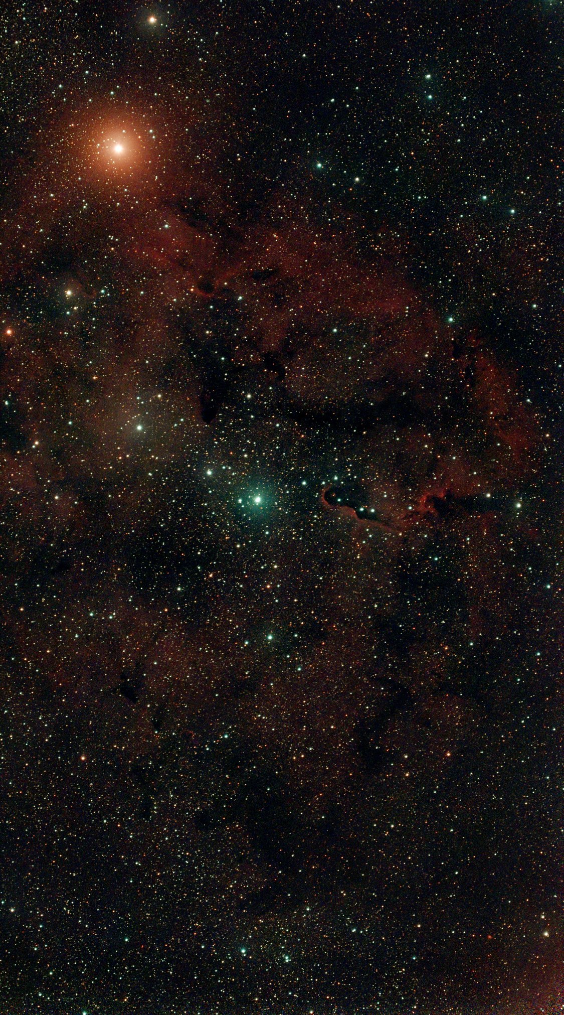 IC 1396: a faint red nebula crossed by dark dust lanes, with the orange Garnet Star at top left and the dark Elephant's Trunk right of centre