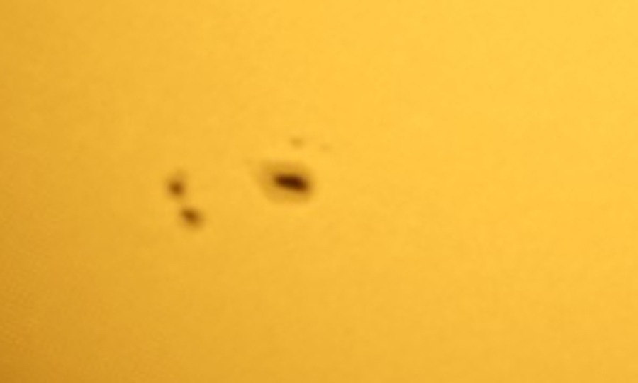 Close-up of the main sunspot group: one large spot with a dark core and lighter fringe, and a smaller pair to its left